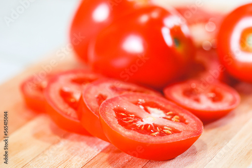 Tomates sobre uma tábua de madeira em fotografia macro. Tomates cortados e tomates inteiros. Alimento, vegetal, orgânico. photo