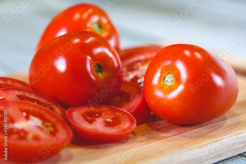 Tomates sobre uma tábua de madeira em fotografia macro. Tomates cortados e tomates inteiros. Alimento, vegetal, orgânico. photo