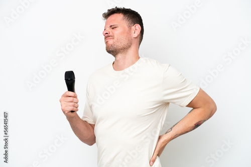 Young caucasian singer man picking up a microphone isolated on white background suffering from backache for having made an effort