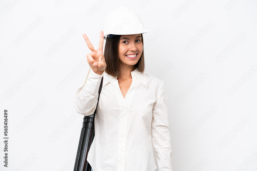 Young architect woman with helmet and holding blueprints isolated on white background smiling and showing victory sign Young architect woman with helmet and holding blueprints isolated on white background smiling and showing victory sign