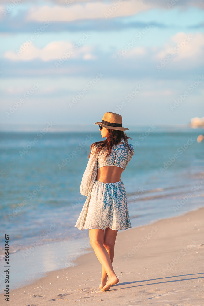 Young happy woman on the beach enjoy her summer vacation. Beautiful woman in hat is happy and calm in her stay on the beach