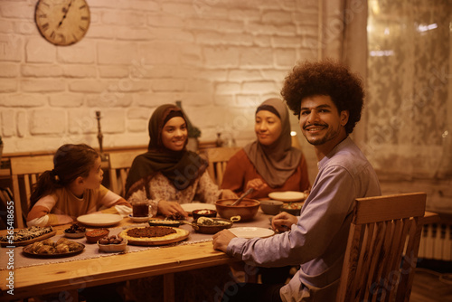 Happy Muslim man and his extended family having dinner at dining table.