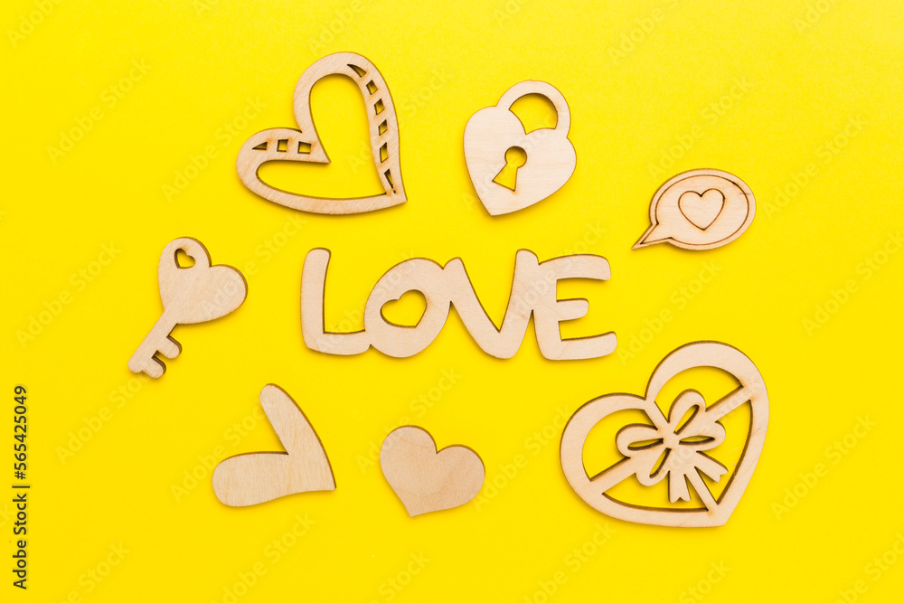 Wooden word love with hearts on color background, top view