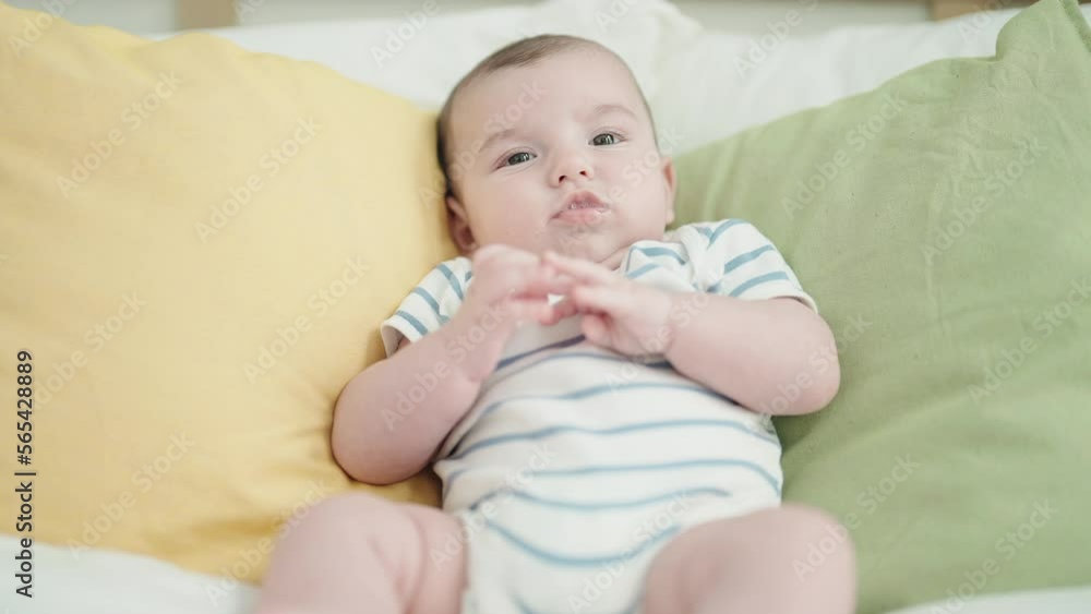 Adorable caucasian baby lying on bed with relaxed expression at bedroom Adorable caucasian baby lying on bed with relaxed expression at bedroom
