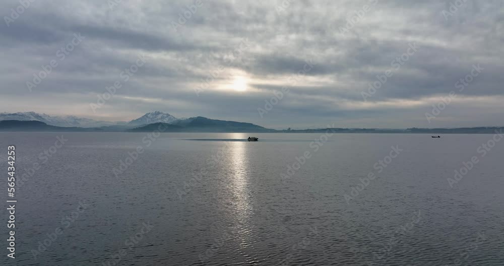 Aerial smooth arc shot of man alone in a tiny boat on a lake on a gloomy winter afternoon Aerial smooth arc shot of man alone in a tiny boat on a lake on a gloomy winter afternoon
