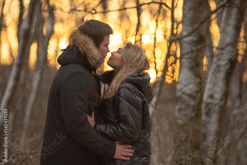 Young couple in love hugging in the winter forest at sunset and having fun spending time together. Winter,Valentine's day,newlyweds, tenderness and love.