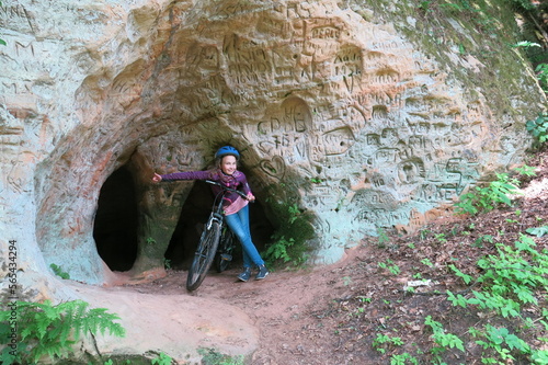 travel with the family on bicycles. person with bike in front of cave in Gauja National Park, Latvia.