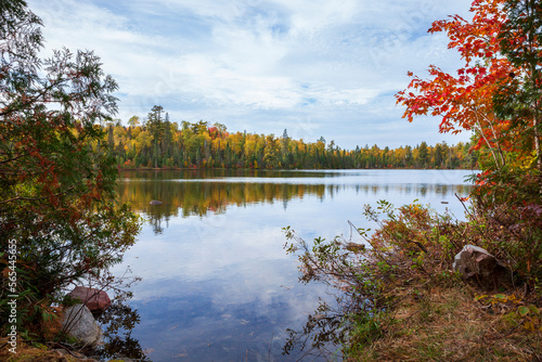 Small lake in northern Minnesota with pines birch and maple trees along the shore during autumn