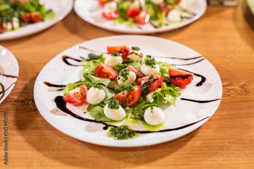 Plate of healthy classic close-up caprese salad with mozzarella cheese tomatoes and basil in kitchen - italian cuisine