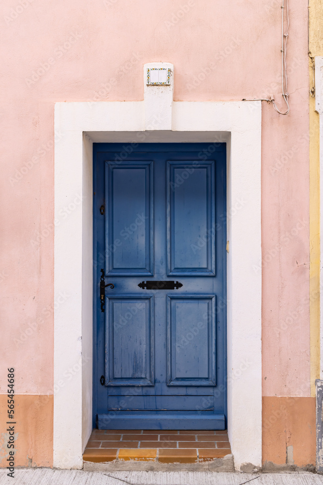 Blue painted door in a pink stucco wall.