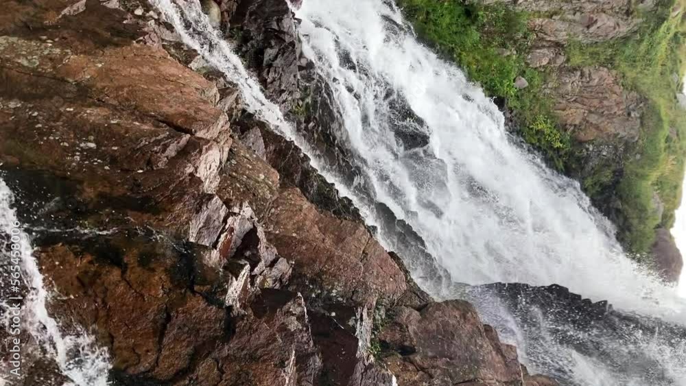 Vertical view of splashing water from a small waterfall to a rocky bottom Vertical view of splashing water from a small waterfall to a rocky bottom