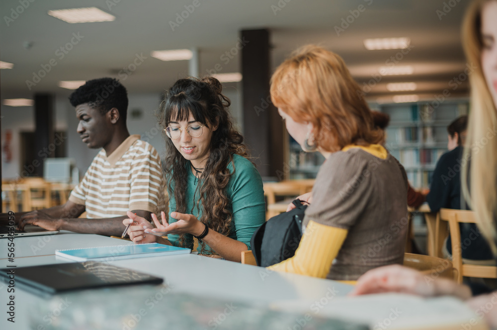 Young diverse groupmates talking in library during exam preparation Young diverse groupmates talking in library during exam preparation