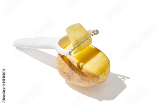 Peeler peeling potato into chips on white background photo