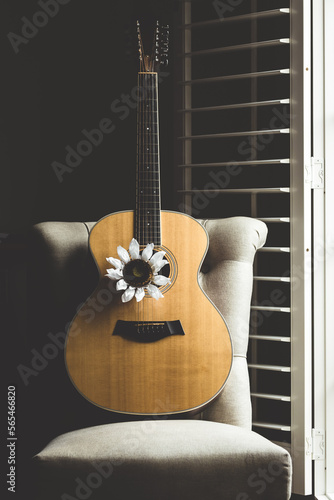 Acoustic guitar on chair with white flower.