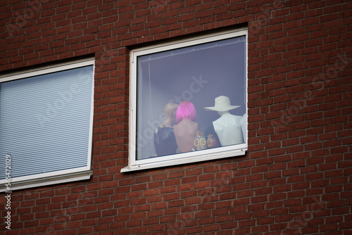 Mannequins with hats and wigs in a window.