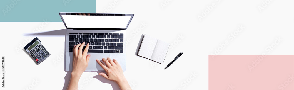 Person using a laptop computer with a notebook Person using a laptop computer with a notebook