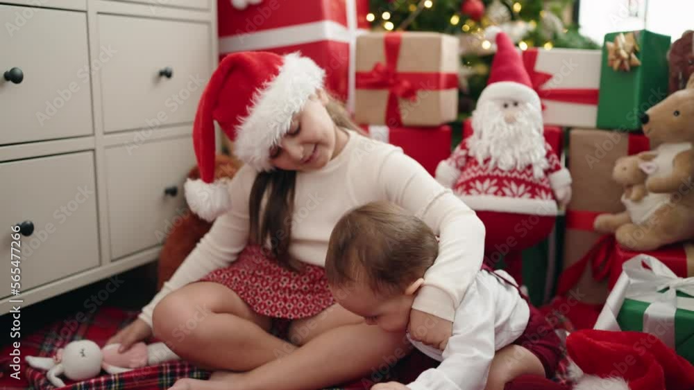 Brother and sister hugging each other sitting on floor by christmas gifts at home Brother and sister hugging each other sitting on floor by christmas gifts at home