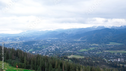 Aerial view of Zakopane town underneath Tatra Mountains taken from the Gubalowka mountain range. Drone High mountains and green hills in summer or spring. Scenic mountain view in Poland. Travel