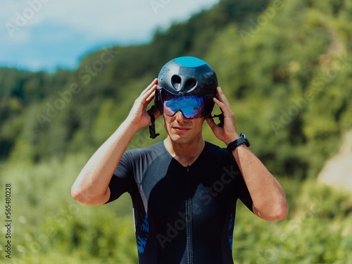 Close up photo of an active triathlete in sportswear and with a protective helmet riding a bicycle. Selective focus