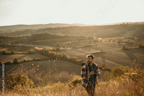 Cheerful man with a digital camera enjoying himself while spending an autumn day on the hill. Copy space.