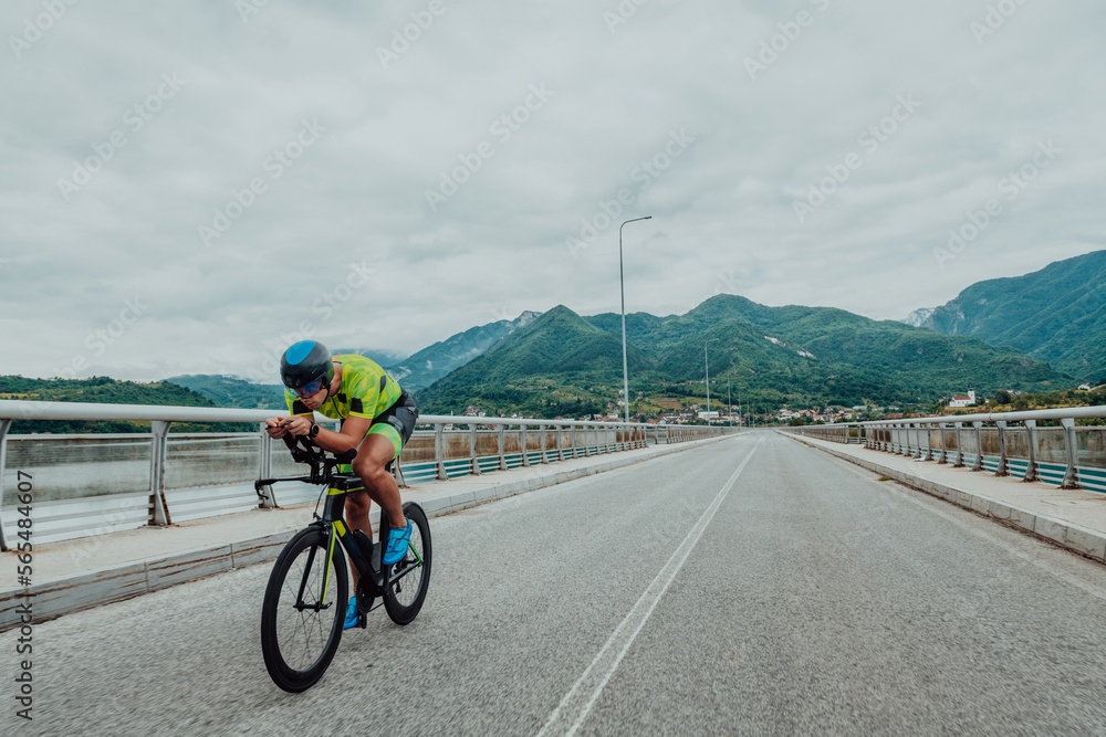 Fototapeta premium Full length portrait of an active triathlete in sportswear and with a protective helmet riding a bicycle. Selective focus 