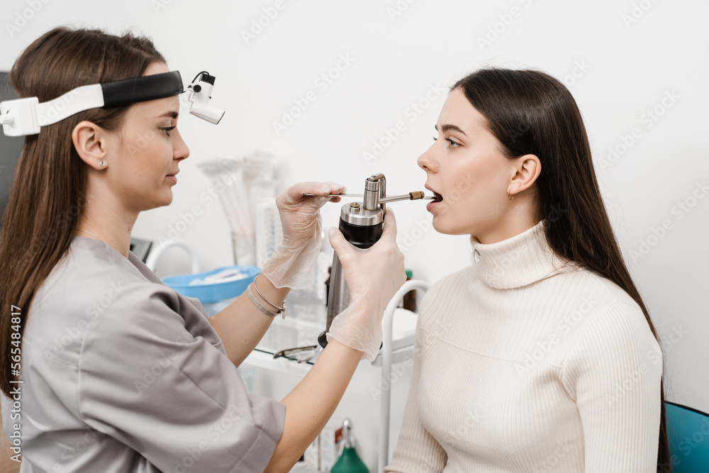 ENT doctor is spraying nitrogen for cryotherapy. Cryo procedures for mucosal renewal and treatment of chronic pharyngitis and tonsillitis. Female doctor otolaryngologist with cryosprayer. ENT doctor is spraying nitrogen for cryotherapy. Cryo procedures for mucosal renewal and treatment of chronic pharyngitis and tonsillitis. Female doctor otolaryngologist with cryosprayer.