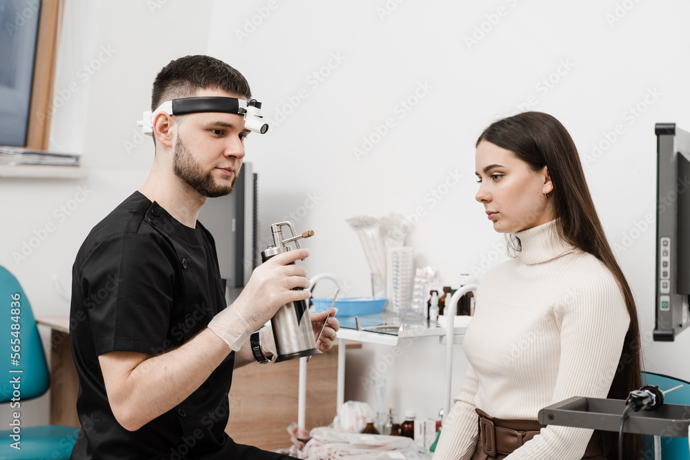 ENT doctor is preparing for nitrogen cryotherapy. Cryo procedures for mucosal renewal and treatment of chronic pharyngitis and tonsillitis. Male doctor otolaryngologist with cryosprayer. ENT doctor is preparing for nitrogen cryotherapy. Cryo procedures for mucosal renewal and treatment of chronic pharyngitis and tonsillitis. Male doctor otolaryngologist with cryosprayer.