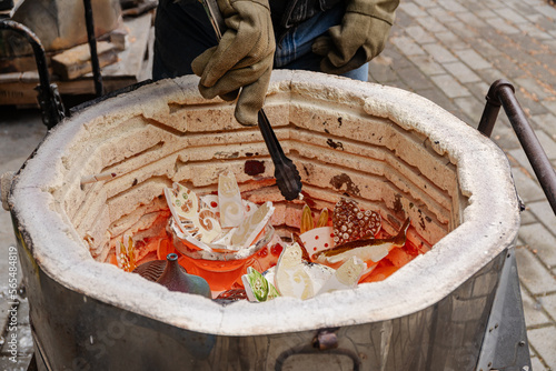 Canvas Print An artist wearing protective gloves loads ceramic raku ware in a red hot kiln