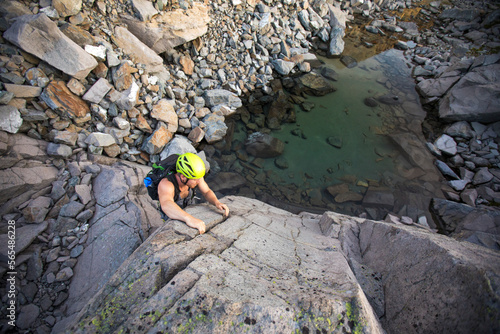 high angle of man bouldering above small alpine tarn. photo