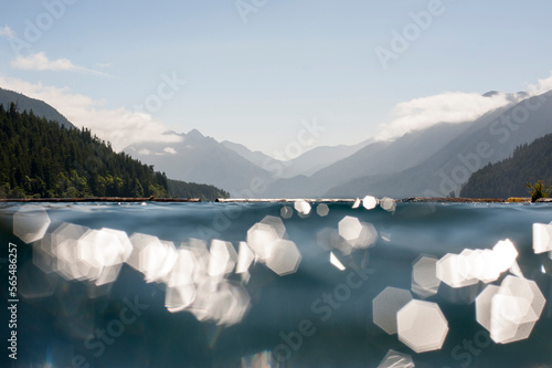 Light refracts off of a lake situated in the mountains.