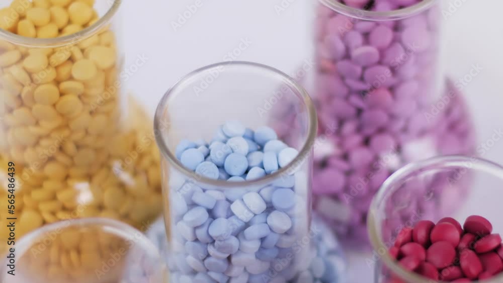 Medical transparent flasks with colored pills rotating on a white background. Healthcare. Medicines, pills. 4K Top view Macro