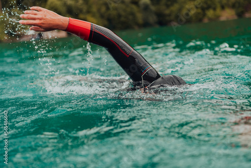 A triathlete in a professional swimming suit trains on the river while preparing for Olympic swimming