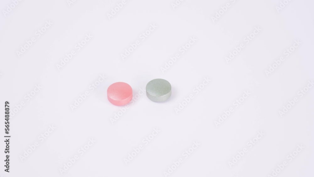 Grey and pink color pills rotate on white background Macro frame Healthcare. Medicines, pills. 4K Space for text Grey and pink color pills rotate on white background Macro frame Healthcare. Medicines, pills. 4K Space for text