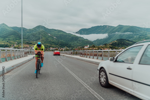 Full length portrait of an active triathlete in sportswear and with a protective helmet riding a bicycle. Selective focus 