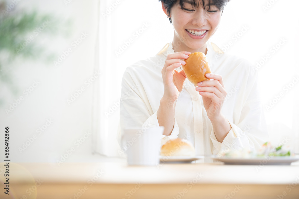 Asian woman eating bread Beautiful fresh breakfast scene with sunrise Green foreground blurring Asian woman eating bread Beautiful fresh breakfast scene with sunrise Green foreground blurring
