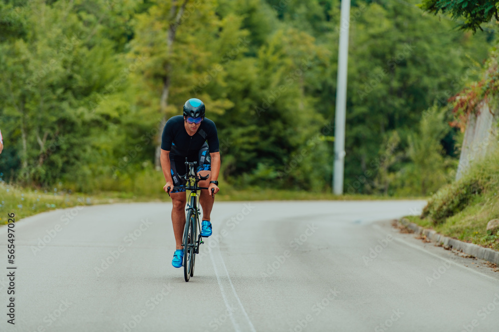 Full length portrait of an active triathlete in sportswear and with a protective helmet riding a bicycle. Selective focus Full length portrait of an active triathlete in sportswear and with a protective helmet riding a bicycle. Selective focus