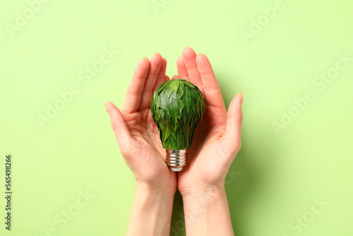 Eco-friendly light bulb with green leaves in woman's hands. Saving energy, protecting the environment and conserving resource concept