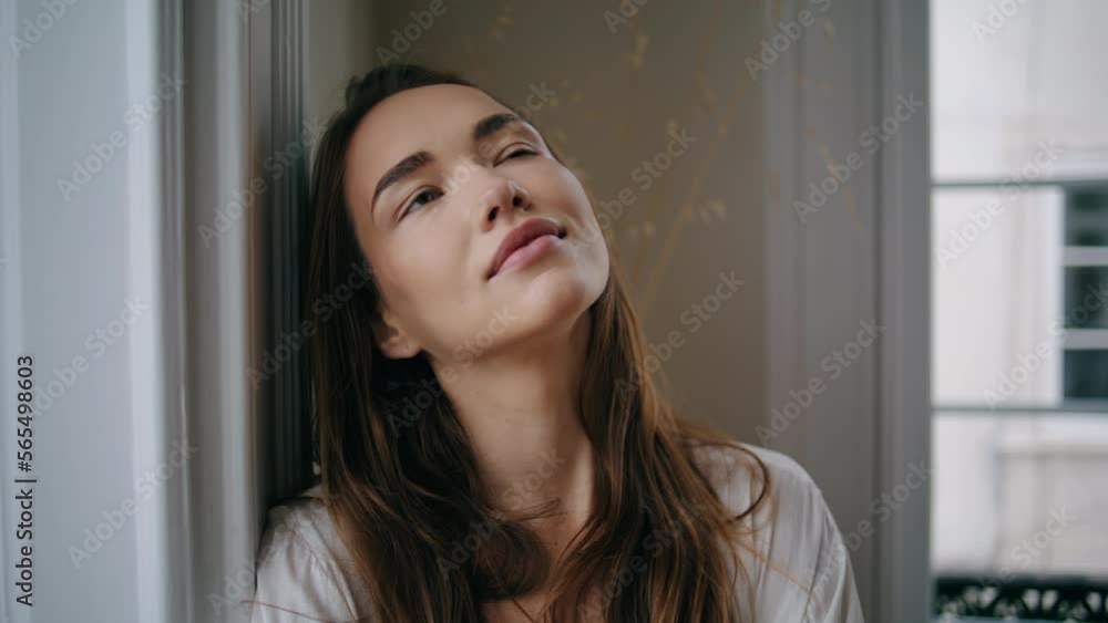Relaxed woman closed eyes windows place close up. Model looking camera at home Relaxed woman closed eyes windows place close up. Model looking camera at home