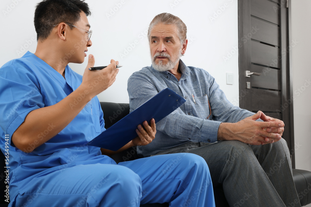 Doctor with clipboard consulting senior patient in clinic Doctor with clipboard consulting senior patient in clinic