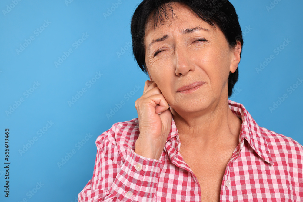 Senior woman suffering from ear pain on light blue background, closeup. Space for text Senior woman suffering from ear pain on light blue background, closeup. Space for text