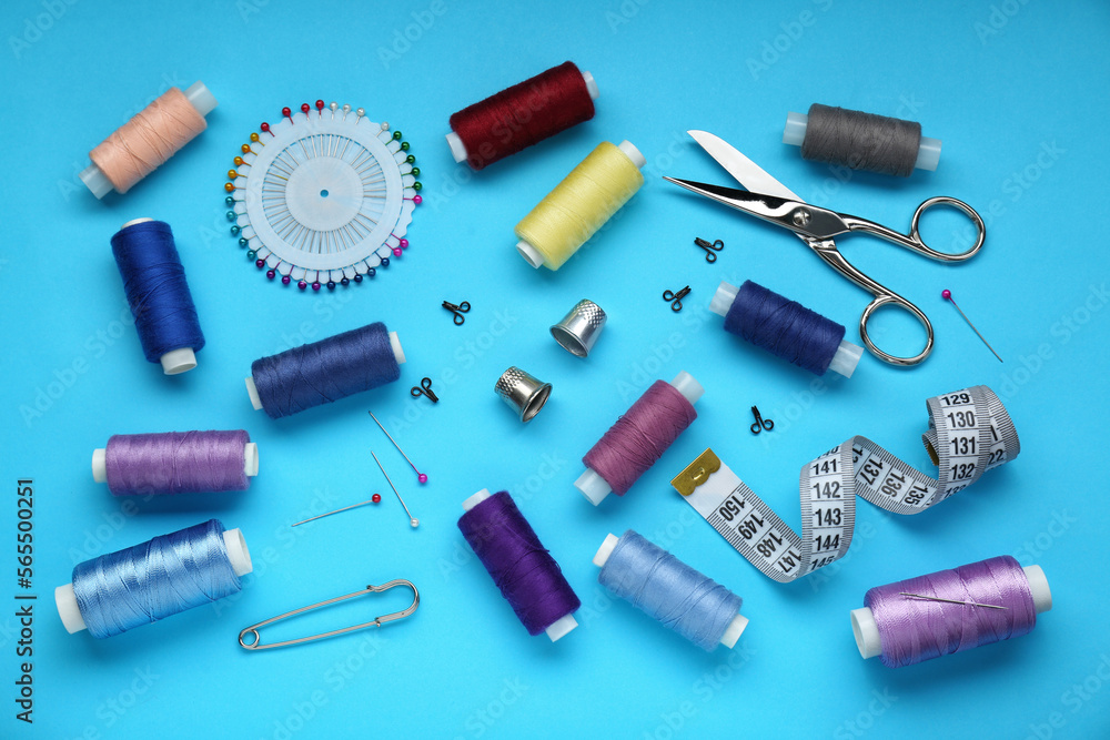 Flat lay composition with thimbles and different sewing tools on light blue background Flat lay composition with thimbles and different sewing tools on light blue background