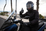 A motorcyclist on his motorcycle gives the thumbs up, happy motorcycle enthusiast