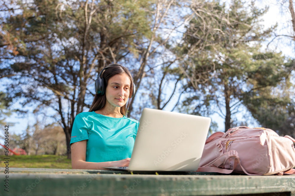 Female university student studying, using a laptop and sitting outside in a park Female university student studying, using a laptop and sitting outside in a park