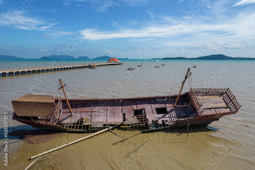 Wrecked abandoned ship against Ko Lanta Old Town pier on sunny day. Krabi Province, Thailand.