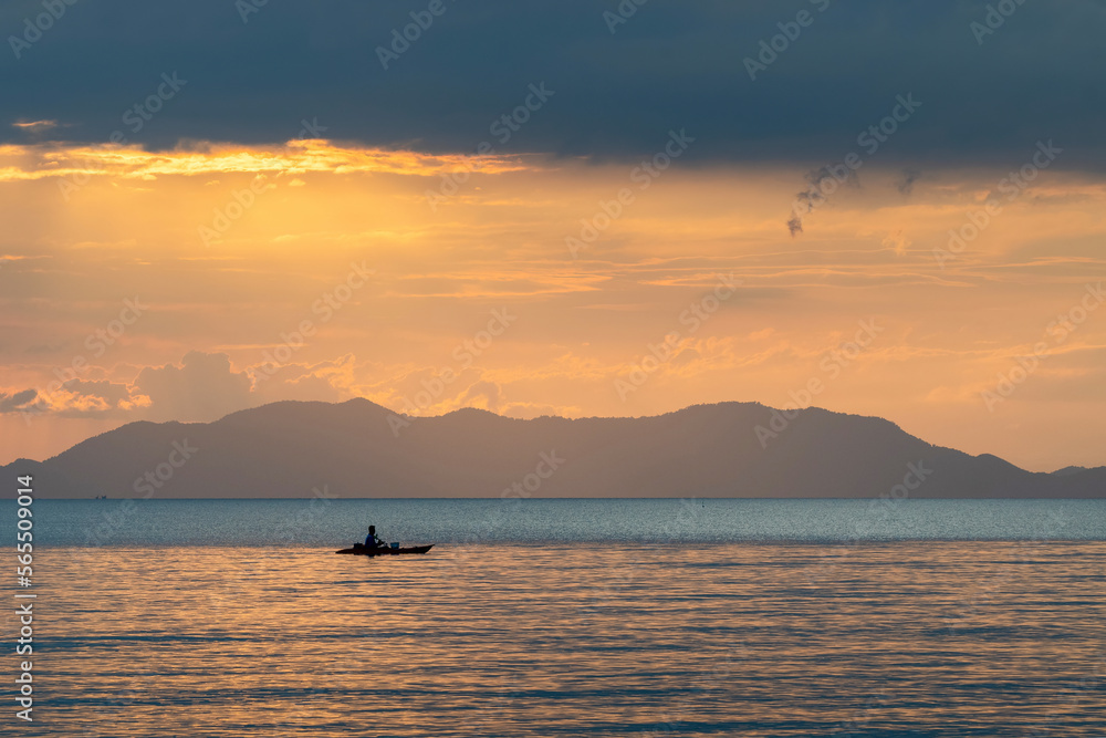 Silhouette of a fisherman on kayak at sunset. View from Klong Muang Beach. Krabi Province, Thailand.