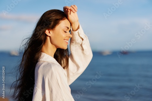 Woman beauty smile with teeth freedom on vacation walking on the beach by the ocean in Bali sunset, happy travel and vacation, sunset light, flying hair, skin and hair care concept in the sun