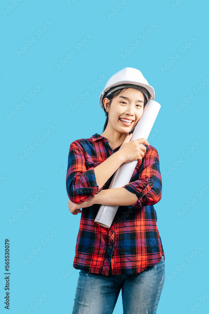 Young female engineer wearing white safety helmet with Blueprints Young female engineer wearing white safety helmet with Blueprints