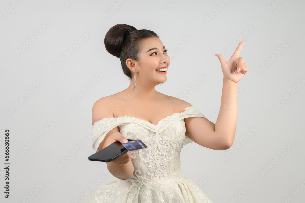 Young asian beautiful bride posting with credit card and smartphone in hand Young asian beautiful bride posting with credit card and smartphone in hand