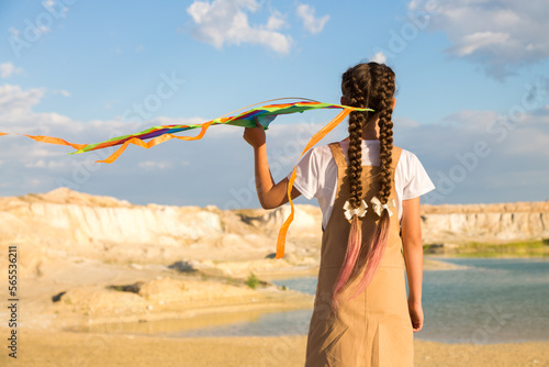 Beautiful teenage girl holding a kite dream to travel to distant countries Back view.