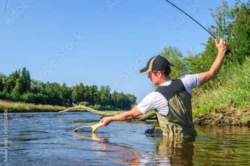 Fliegenfischer mit Fischkescher in Aktion photo